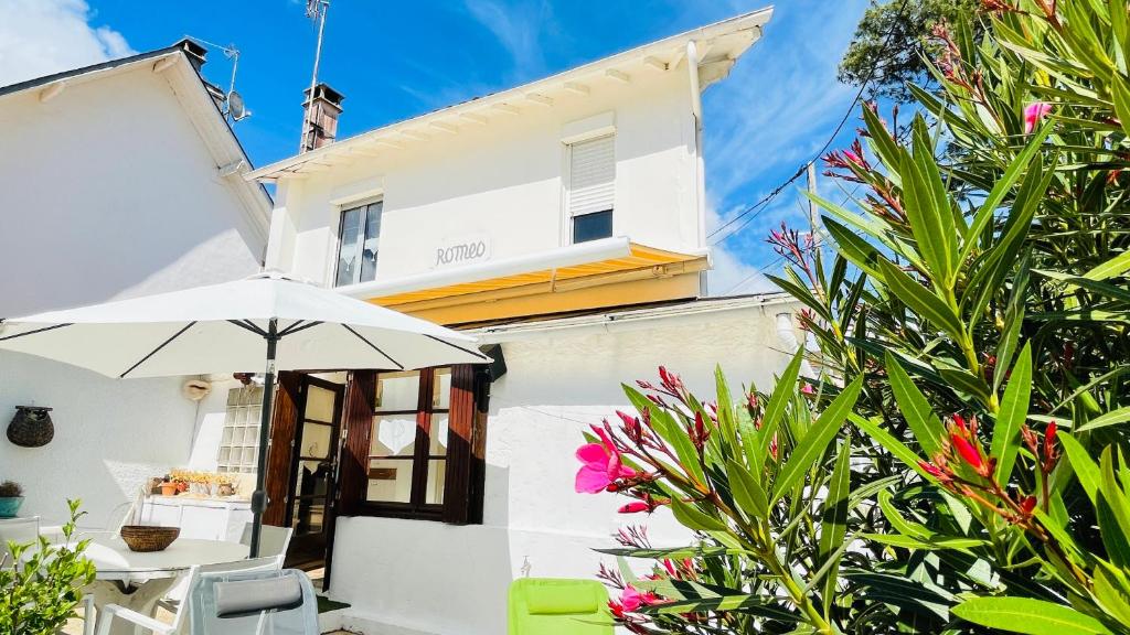 une maison blanche avec un parasol et quelques plantes dans l'établissement Villa ROMEO , 250M de la plage, à Saint-Georges-de-Didonne