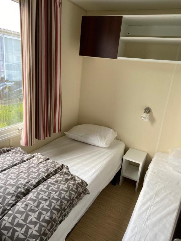 Cette petite chambre comprend 2 lits et une fenêtre. dans l'établissement Camping le Clos Savoye, à Biville-sur-Mer