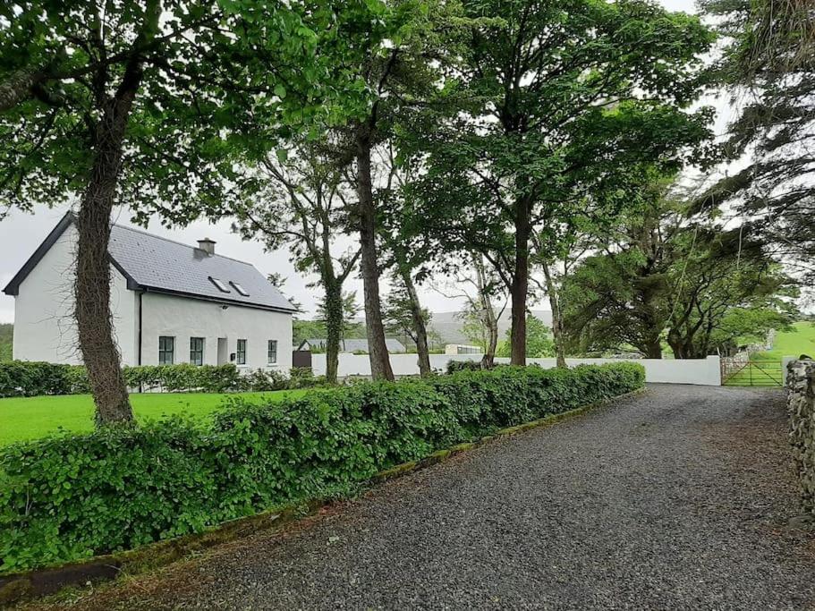 a driveway leading to a white house with trees at Traditional Cosy Cottage with beautiful views in Westport