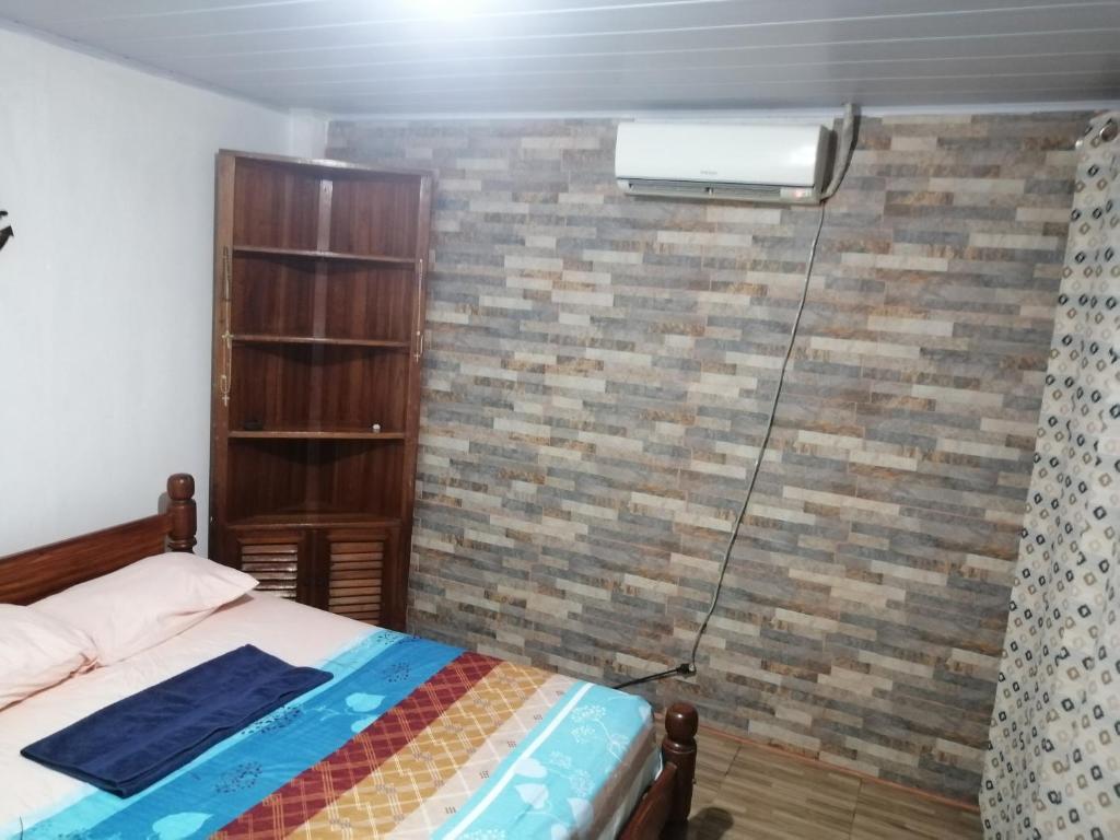 - une chambre avec un lit et un radiateur sur un mur en briques dans l'établissement APARTA-Refugio El Retiro Verde, à Leticia