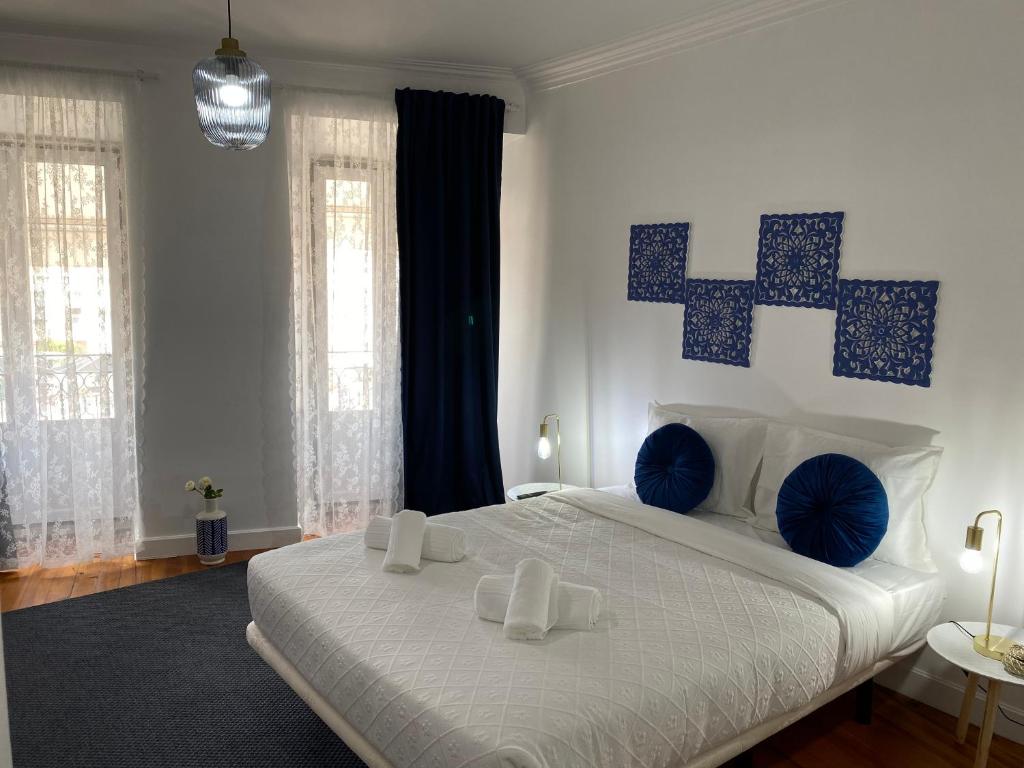 a bedroom with a large white bed with blue pillows at Memórias de Setúbal AL in Setúbal