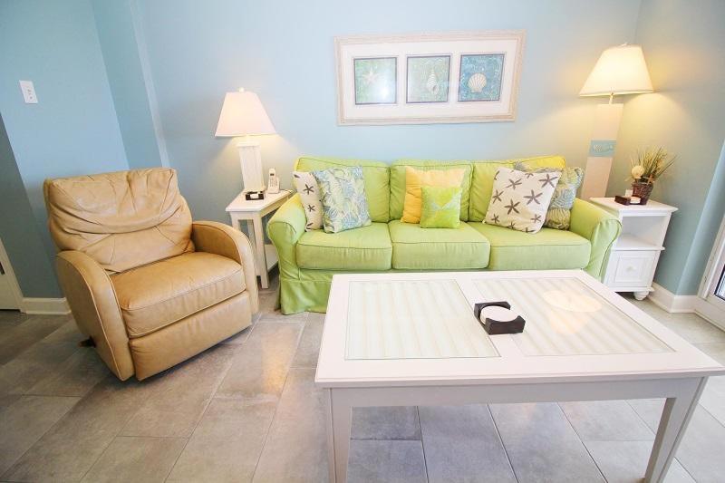 uma sala de estar com um sofá verde e uma cadeira em Tradewinds 1102 condo em Orange Beach