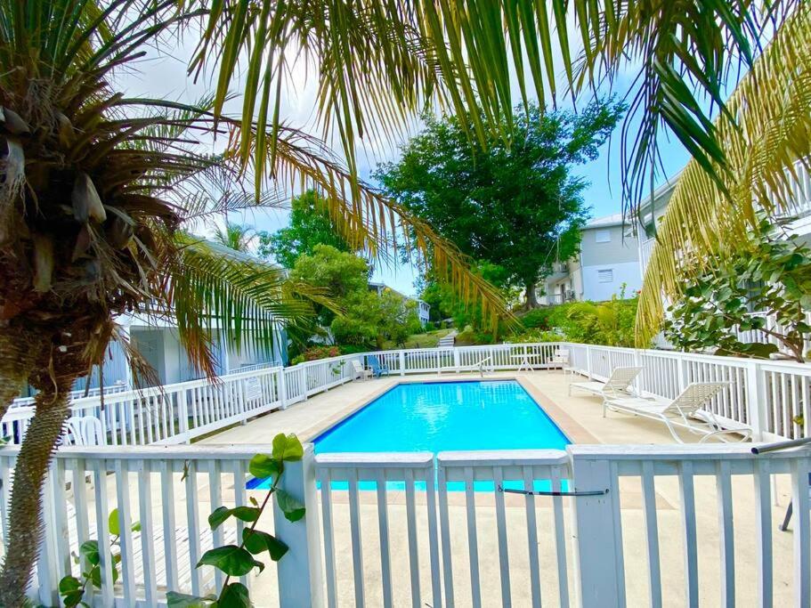 a swimming pool with a white fence and palm trees at Breezy Nights St. Croix in Christiansted