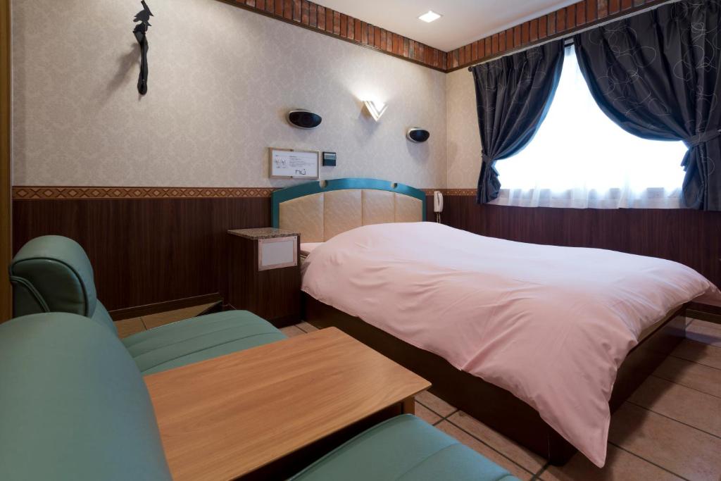 大阪市にあるホテル フー難波（大人専用）のベッド1台、椅子2脚、窓が備わる客室です。