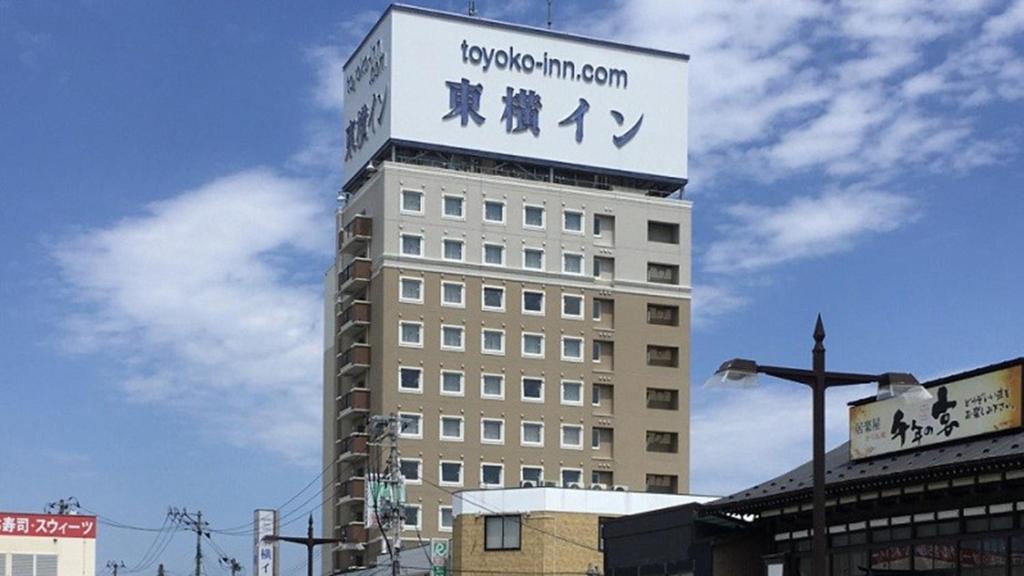 wysoki budynek z znakiem na górze w obiekcie Toyoko Inn Hachinohe Ekimae w mieście Hachinohe