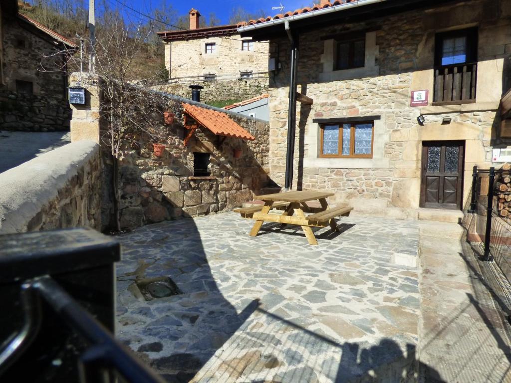 una mesa de picnic de madera frente a un edificio de piedra en "Apartamento Peña Sagra", en San Mamés