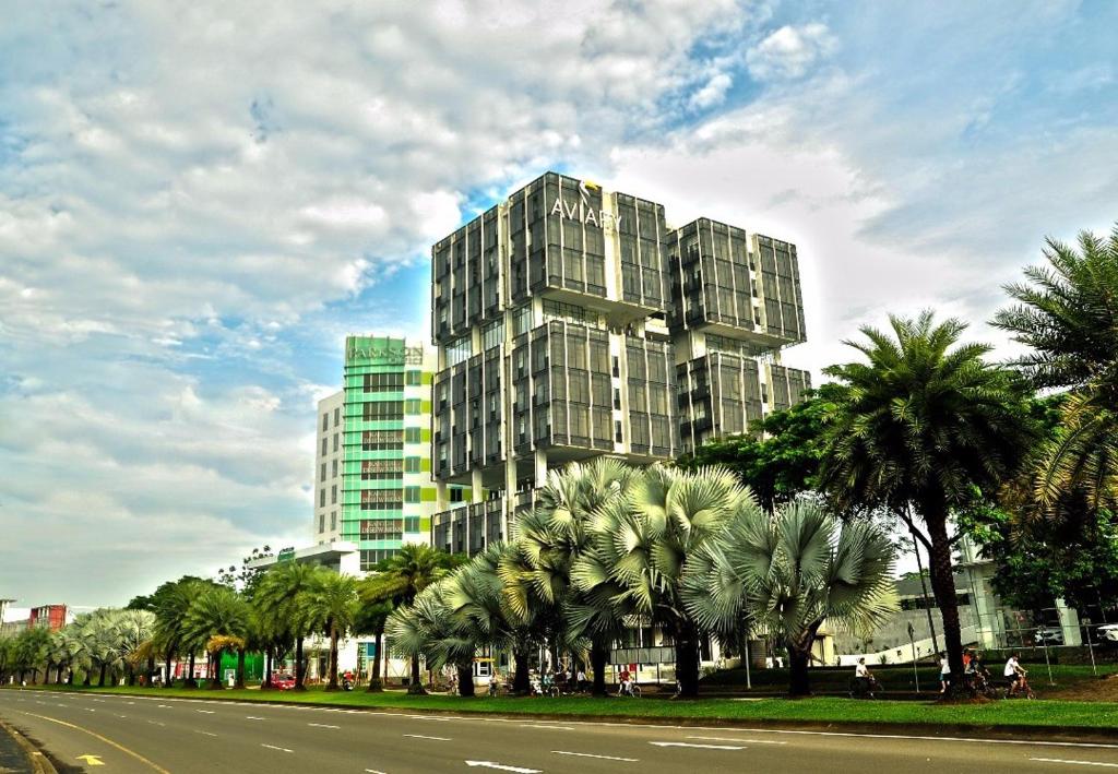 a tall building with palm trees in front of a street at Aviary Bintaro in Serpong