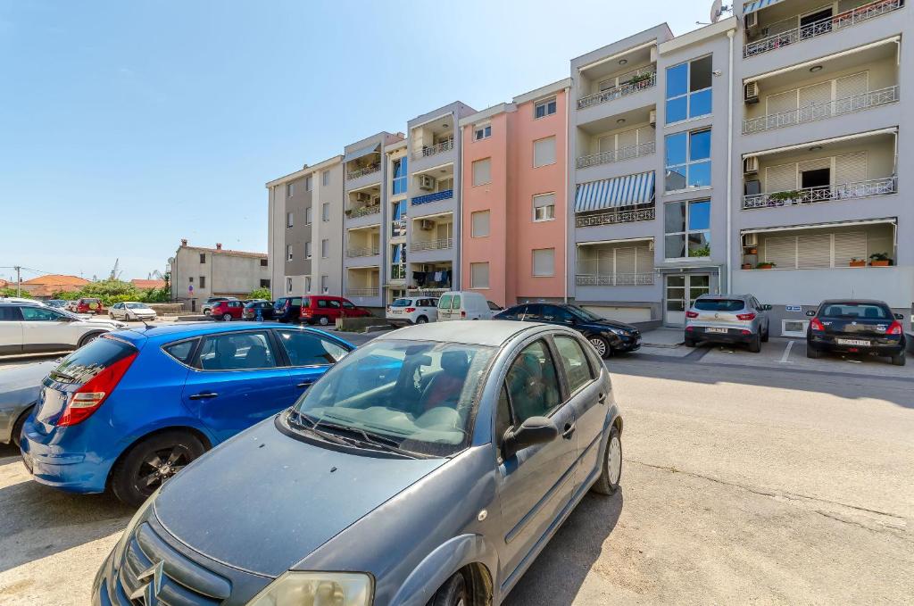 ein blaues Auto, das auf einem Parkplatz vor den Gebäuden parkt in der Unterkunft Apartment Dora in Trogir