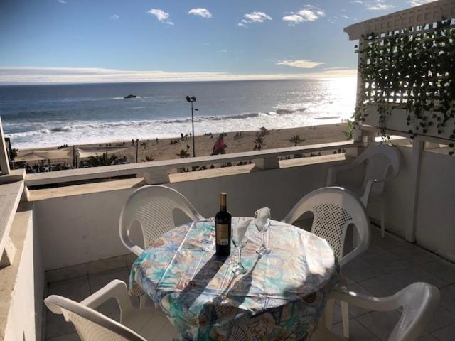a table with a bottle of wine sitting on a balcony with the beach at Ocean View in Viña del Mar