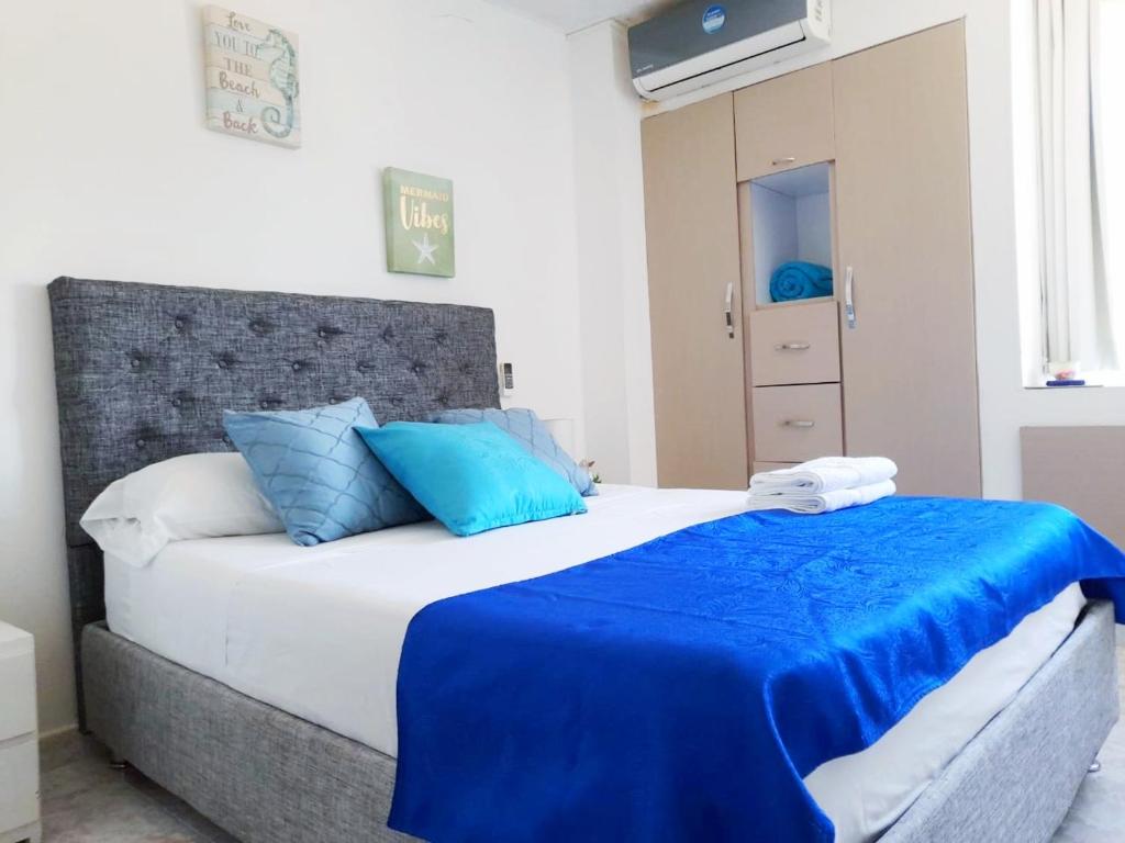 a bedroom with a large bed with blue pillows at Apartamento rodadero playa y diversion in Santa Marta