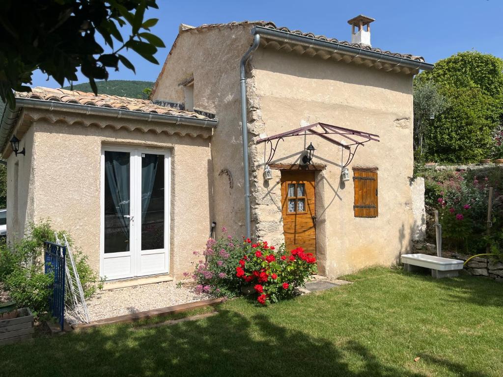 una pequeña casa con una puerta y flores en el patio en Cabanon entouré de montagnes et d'oliviers, en Nyons