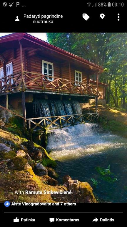 a picture of a log cabin next to a river at Gazdų Vandens Malūnas in Navininkai