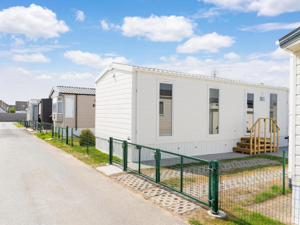 ein weißes Haus mit einem Zaun davor in der Unterkunft Modern mobile home in Middelkerke with garden in Middelkerke