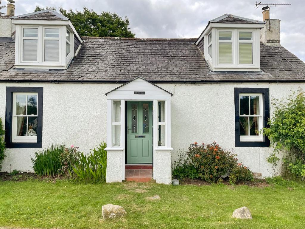 Casa blanca con puerta verde y ventanas en Strathannan en Moffat