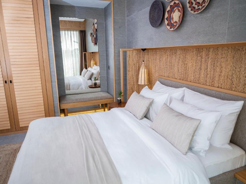 a bedroom with a large white bed and a mirror at Sa'Rezya Hotel in Çeşme