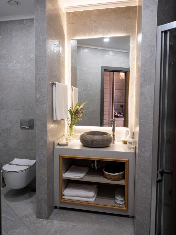 a bathroom with a sink and a toilet and a mirror at Sa'Rezya Hotel in Çeşme