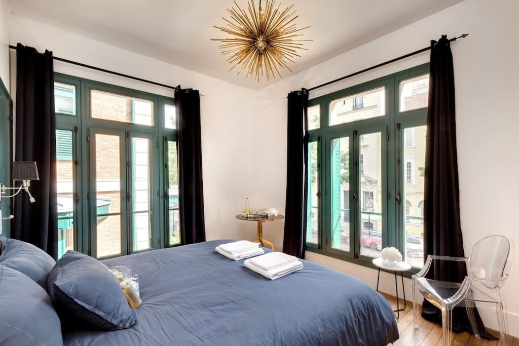 sypialnia z niebieskim łóżkiem i dużymi oknami w obiekcie Pavillon indépendant en plein centre de Vichy w mieście Vichy