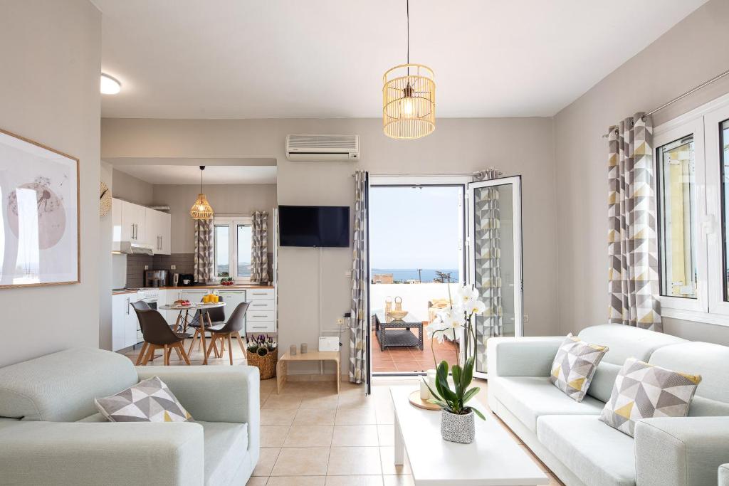 a living room with white furniture and a kitchen at Plaka Modern Apartment in Chania Town