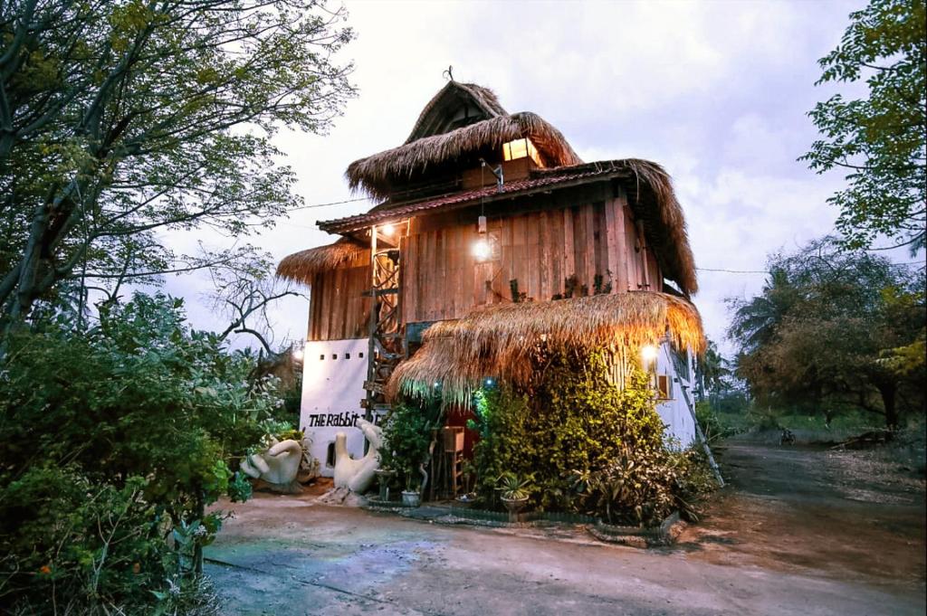 a small house with a thatch roof at The Rabbit Tree Hostel in Gili Meno