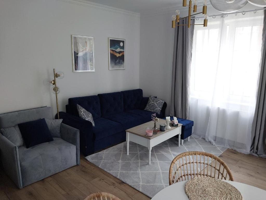 a living room with a blue couch and a table at APARTAMENT PIASTOWSKI in Polanica-Zdrój