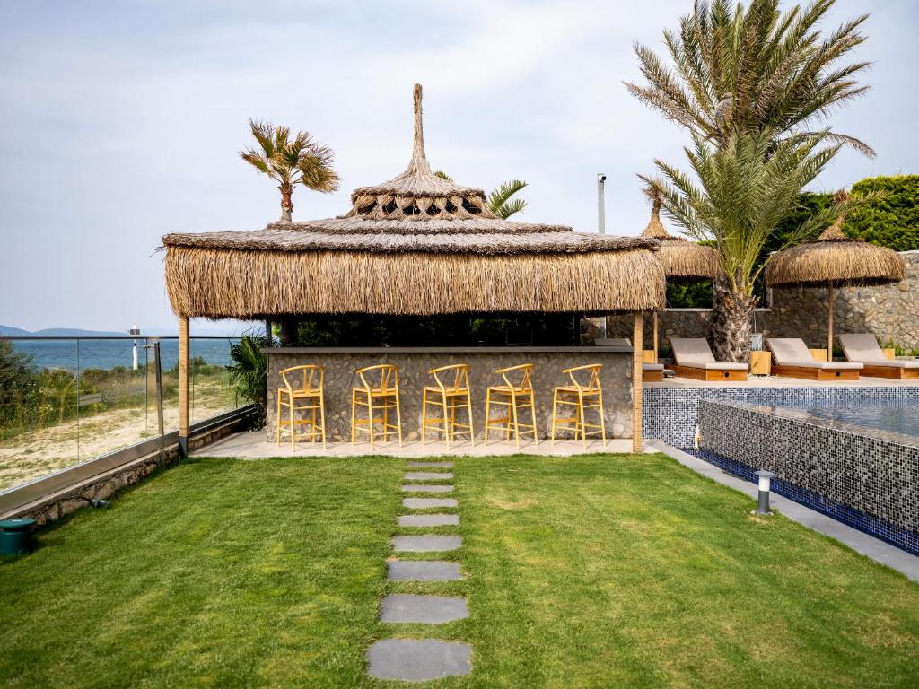 a resort with a grass roof and a yard with chairs at Sa'Rezya Hotel in Çeşme