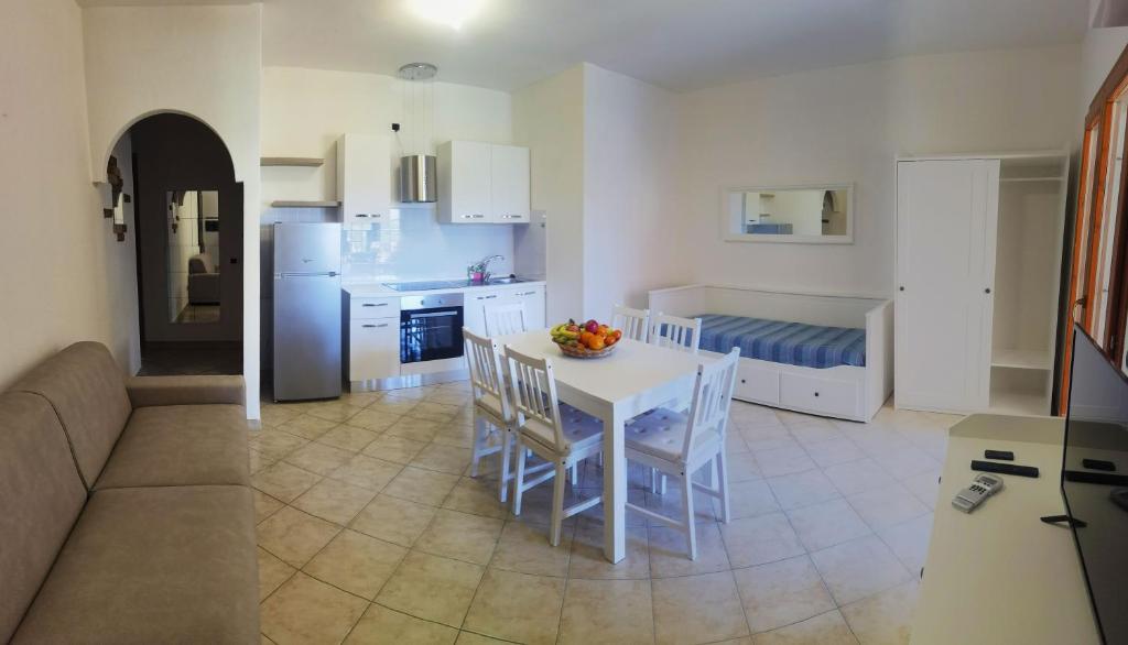 une cuisine et un salon avec une table et des chaises blanches dans l'établissement Residence Nausicaa, à Santa Teresa Gallura