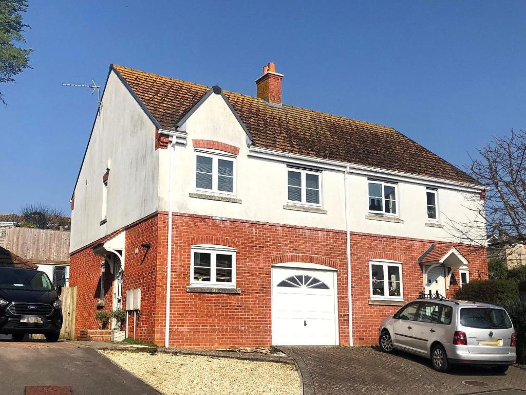 a white and red brick house with a car parked in front at Anning's View in Lyme Regis