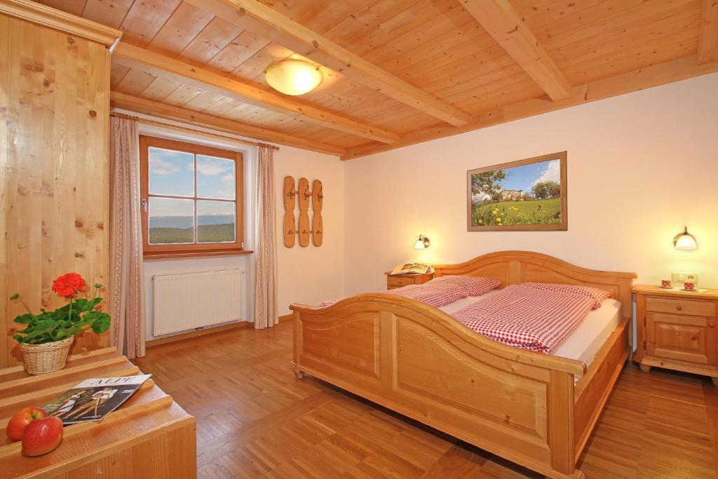 sypialnia z drewnianym łóżkiem i oknem w obiekcie Niglutsch Apartement Kastelruth w mieście Castelrotto