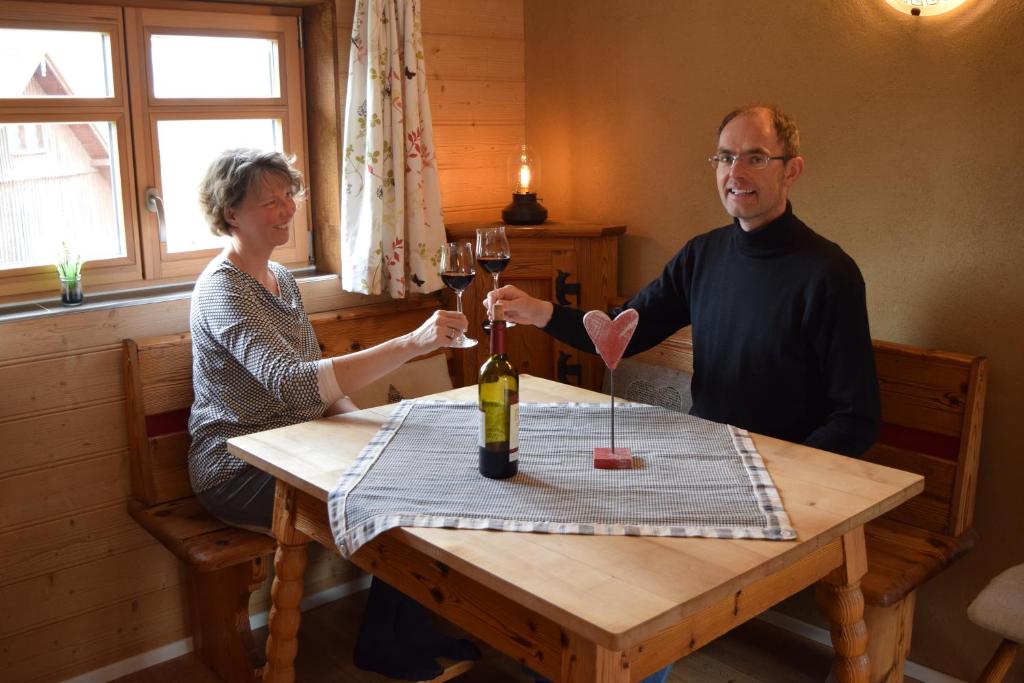 a man and woman sitting at a table with wine glasses at Holstein-Höfle - Gipfelstüble in Argenbühl