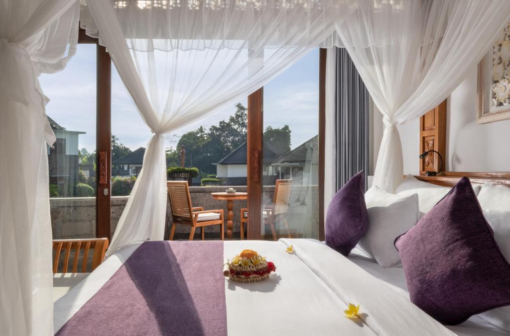 a bedroom with a bed and a table with food on it at Swan Paradise A Pramana Experience in Gianyar