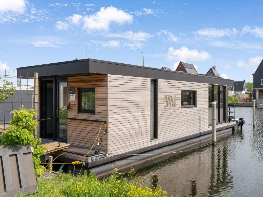a house on a boat on a body of water at Brand new Boathouse on the water in Stavoren with a garden in Stavoren