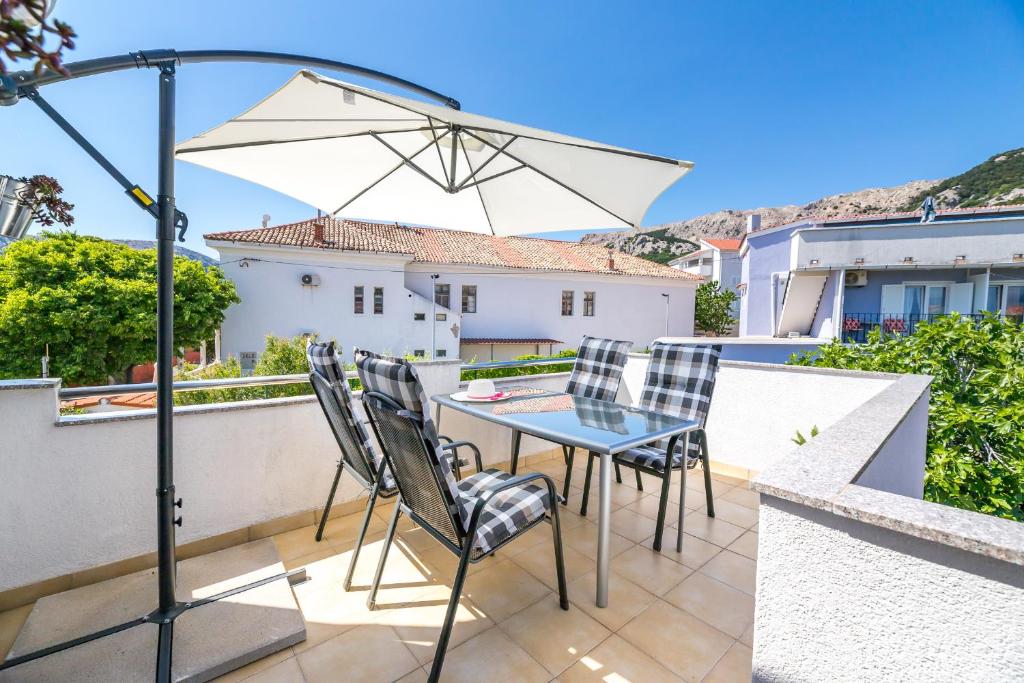 Un patio con una mesa y sillas y una sombrilla. en Ana, en Baška