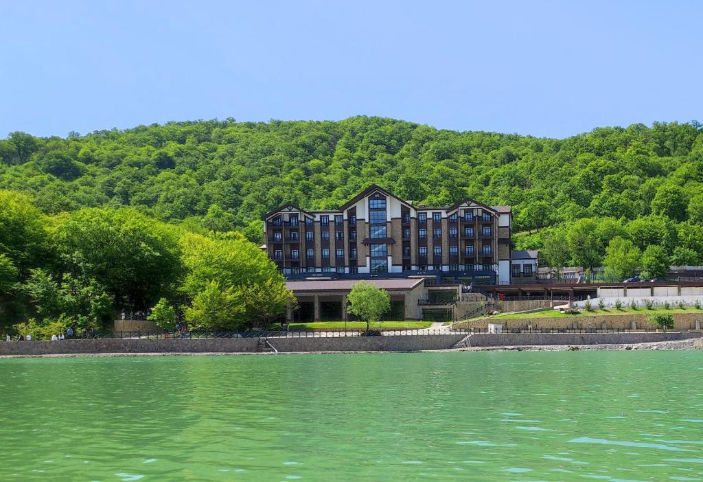 a large building on the shore of a body of water at Macara Lake Park in Quba