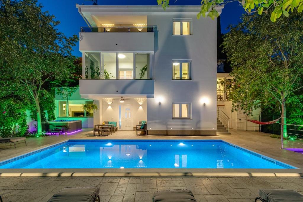 une villa avec une piscine en face d'une maison dans l'établissement New Villa Zara with 32 sqm heated Pool, Jacuzzi, Billiard, Tennis table, 8pax, à Kučiće