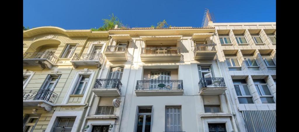 un edificio alto de color blanco con balcones en un lateral. en Dioskouros Hostel en Athens
