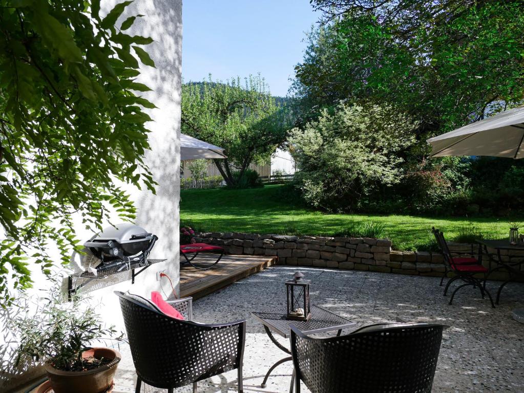 a patio with chairs and a grill in a yard at Helles 2-Zimmer-Apartment in Ostin am Tegernsee in Gmund am Tegernsee