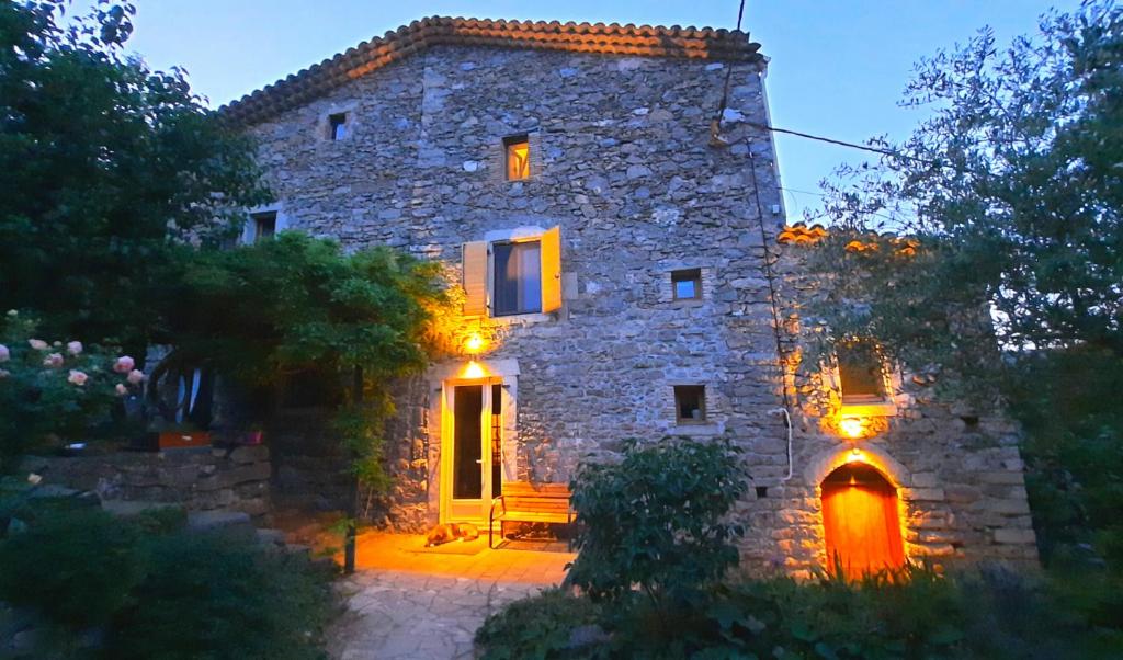 - un grand bâtiment en pierre avec un banc devant dans l'établissement Mas de Boissière - Chambres d'hôtes avec piscine et jacuzzi, à Cros