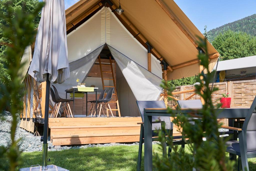 une tente avec une table et des chaises dans l'herbe dans l'établissement Comfort Safarizelt direkt am Ossiachersee, à Steindorf am Ossiacher See