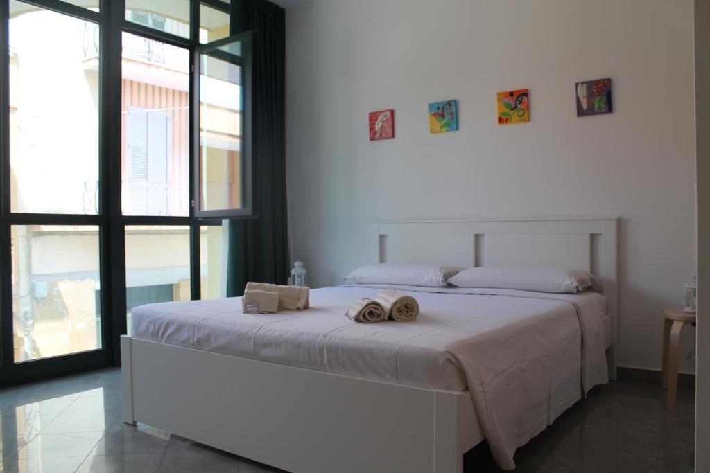 una camera da letto bianca con un letto con due asciugamani sopra di Studio 60 Holiday a Galatina