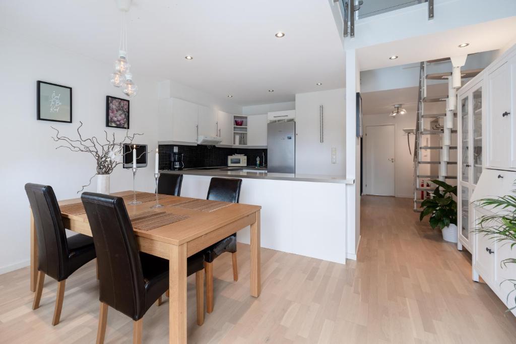 a kitchen and dining room with a wooden table and chairs at Central top floor apartment in Stavanger
