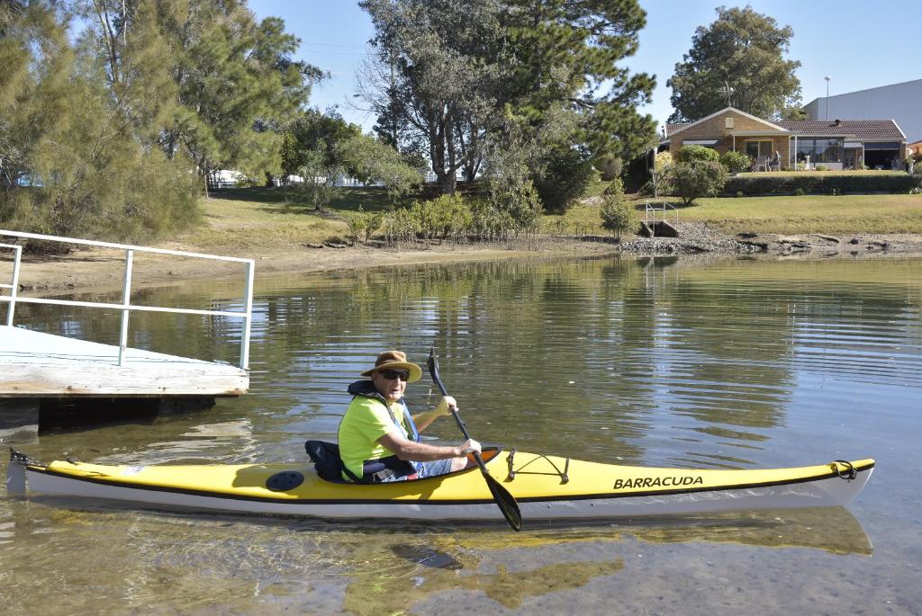 un hombre en un kayak amarillo en el agua en Port O'Call Motel, en Port Macquarie