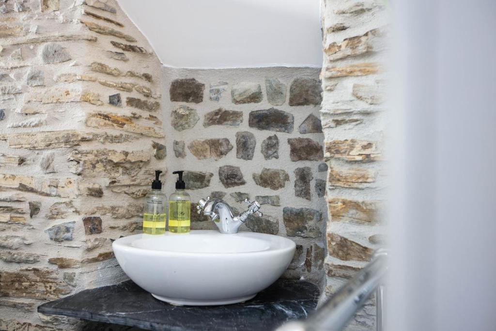 a bathroom with a sink in a stone wall at The Olde Malthouse Inn in Tintagel