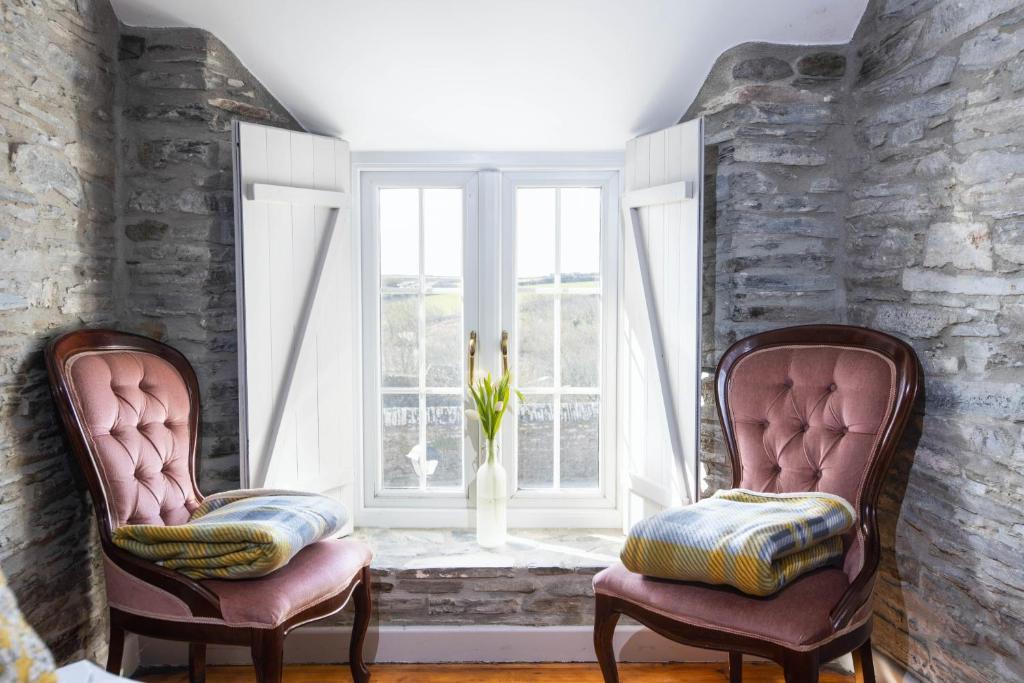 two chairs sitting in a room with a window at The Olde Malthouse Inn in Tintagel