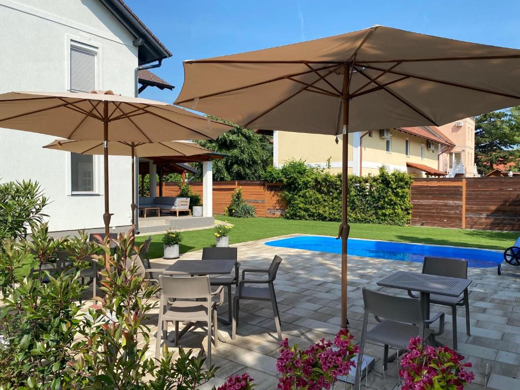 a patio with tables and chairs and umbrellas at Best Apartman Lelle in Balatonlelle