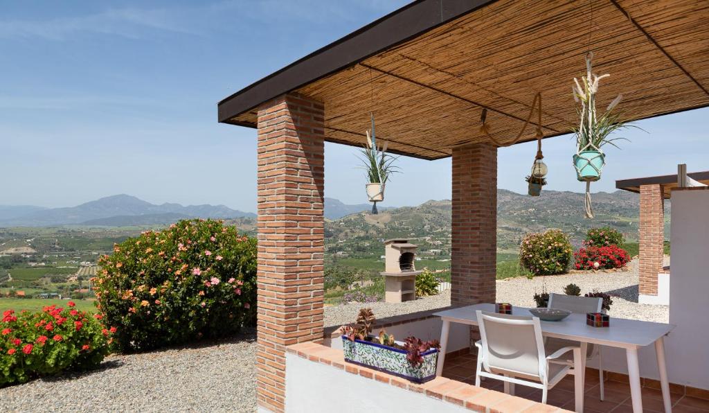 a patio with a table and chairs and flowers at Finca Feliz Andaluz in Alora