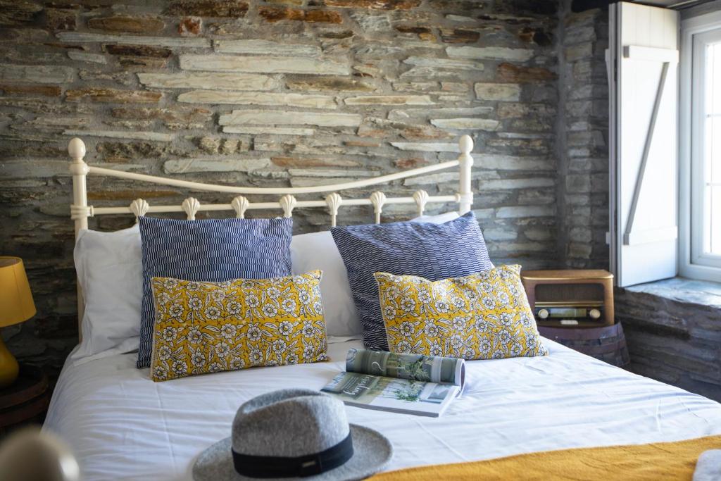 a bedroom with a bed with pillows and a brick wall at The Olde Malthouse Inn in Tintagel