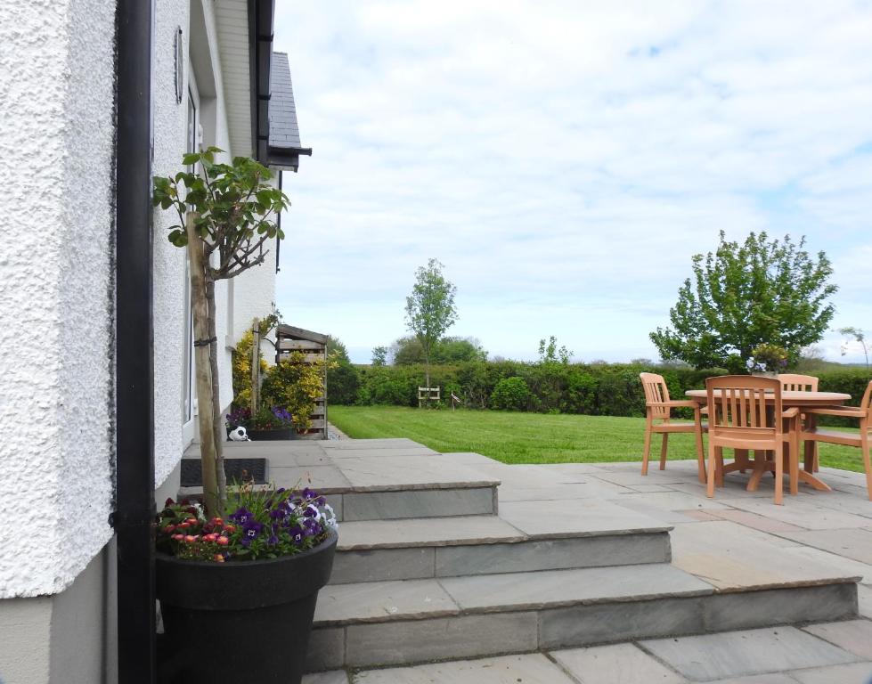 a patio with stairs and a table and chairs at Meadow Cottage in Bushmills