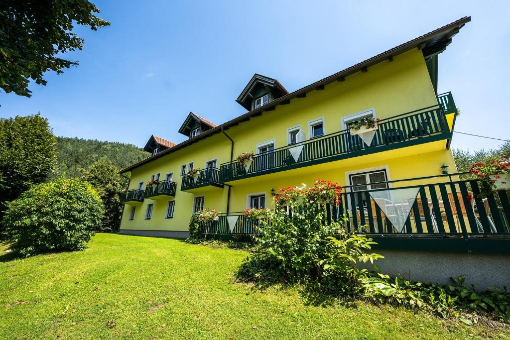 une grande maison jaune avec un balcon et une cour dans l'établissement Bauernhof Podorn, à Sankt Kanzian