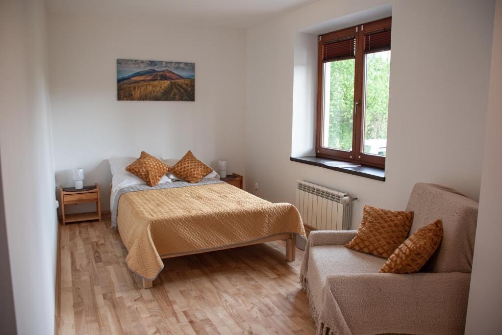 een slaapkamer met een bed, een bank en een raam bij Noclegi Kalniczka in Tarnawa Dolna