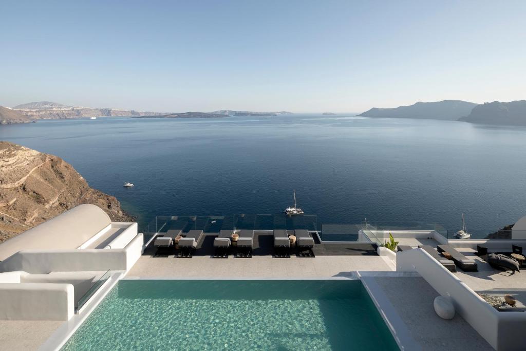 a swimming pool with chairs and a view of the water at Hom Santorini in Oia